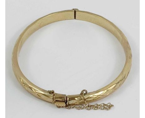 A 9 carat gold hinged bangle, with facetted decoration, inner diameter approximately 6.2cm, 6.8g gross