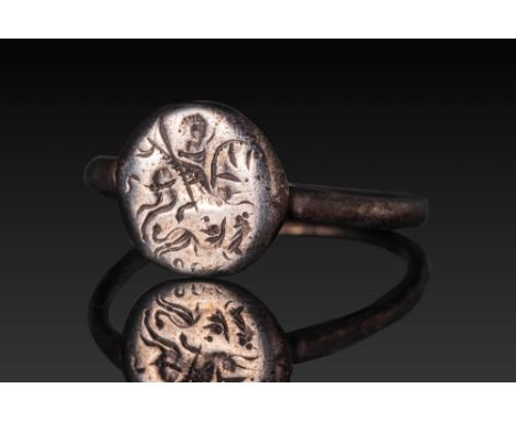 Ca. AD 500 - 700. A silver ring with a flat circular bezel engraved with a stylised scene of St. George on horseback spearing