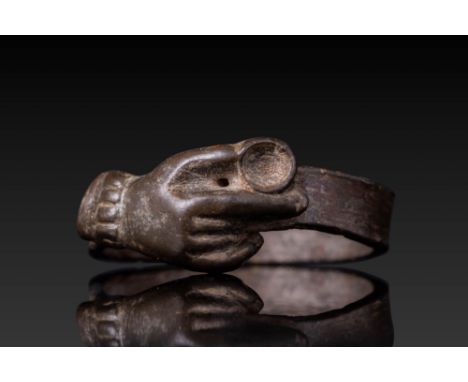 Ca. AD 1400 - 1600. A bronze ring with a flat hoop, surmounted by a raised bezel in the form of a right hand, with the thumb 
