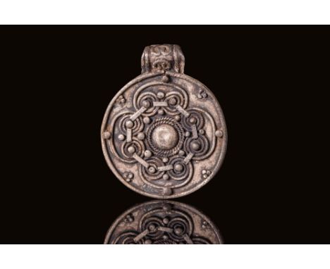 Ca. AD 800 - 1100. A silver medallion with a circular form and suspension loop. The central field is decorated with a domed b