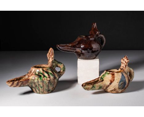 Ca. AD 1000 - 1200. A collection of three glazed terracotta oil lamps, each with a globular body, long channelled spout, and 