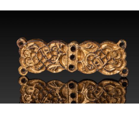 Ca. AD 500 - 700. A gilt-bronze belt applique of elongated, symmetrical form with a central vertical ridge pierced by three c