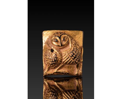 Ca. AD 900 - 1200.A nearly square bronze-gilt plaquette with a repoussé owl in frontal view, with a rounded body, incised win