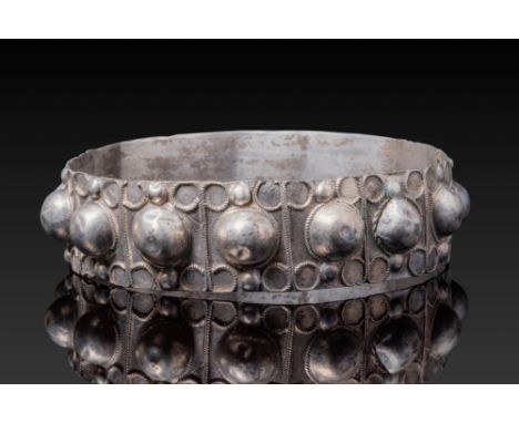 Ca. AD 900 - 1100. A bracelet formed from a broad silver band with a continuous frieze of raised hemispherical bosses set wit