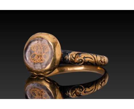 Ca. AD 1800. A gold mourning ring with a circular bezel enclosing a transparent layer above a gold scrollwork monogram, set o