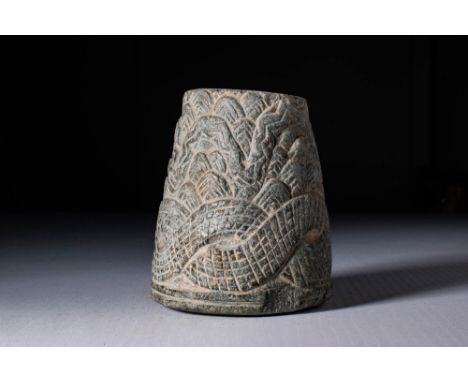 Ca. 2600 - 2400 BC. A stone jar with a tapered body and a flat base. The exterior is intricately incised with a coiled snake 