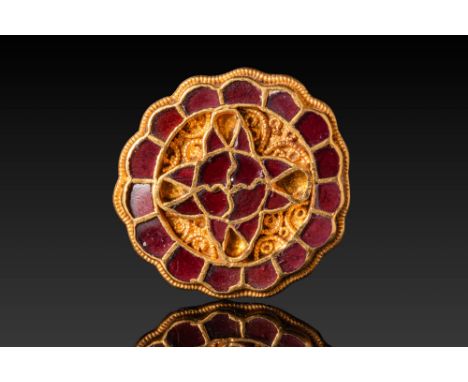 Ca. AD 560 - 650. A circular gold brooch with a scalloped outer edge and a cloisonné-decorated surface. The central motif con