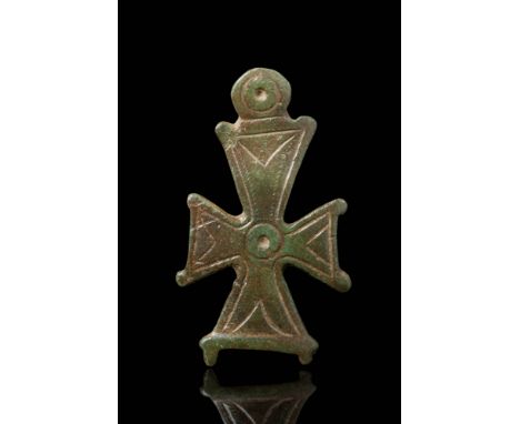 Ca. AD 900 - 1100. A bronze cross-shaped fitting with flaring arms decorated with incised linear and circular motifs. Each co