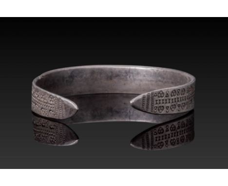 Ca. AD 900 - 1100. A solid silver bracelet of penannular form with tapering terminals. The exterior is decorated with stamped