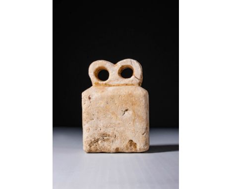 Ca. 3700 - 3500 BC. A rectangular stone idol surmounted by a pair of deeply recessed circular eyes carved in high relief.For 