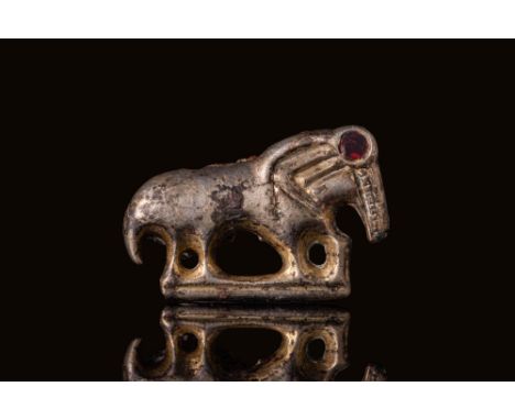 Ca. AD 600 - 700. A silver-gilt brooch plate depicting a mythological quadruped rendered in profile. The body is compact and 