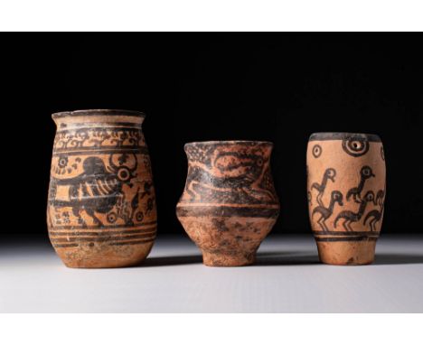 Ca. 2500 - 2000 BC.A collection of three pottery cups, each decorated in black over reddish or buff slip. The first is roughl