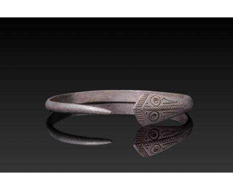 Ca. AD 100 - 300. A Celtic crafted silver bracelet with a flattened band that gracefully tapers to an open end. One end featu