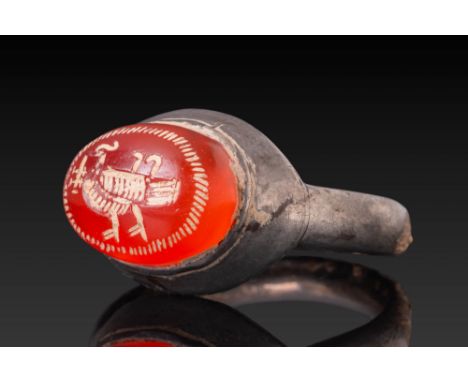 Ca. AD 200 - 600. A carnelian intaglio engraved with a stylised bird with prominent tail feathers, possibly a peacock, enclos
