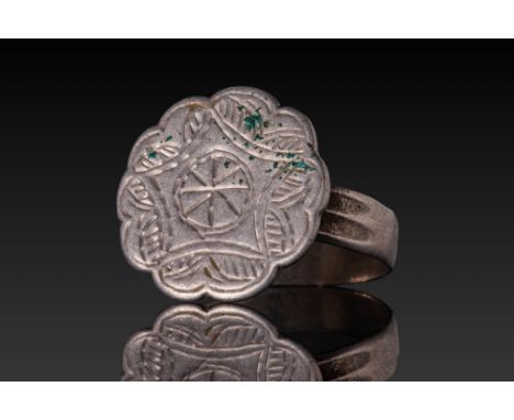 Ca. AD 1400 - 1600. A silver ring with a flat hoop and a large bezel shaped as a scalloped disc, engraved with a central five