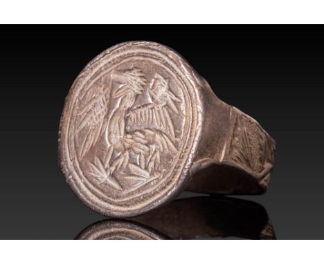 Ca. AD 1200 - 1400.A silver alloy ring with a broad circular bezel engraved with a stylised dragon with outstretched wings. T
