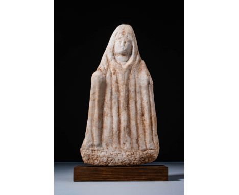 Ca. AD 300 - 400. A marble relief depicting a Genius Cucullatus. The figure is shown frontally, wearing a deeply pleated mant