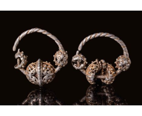 Ca. AD 900 - 1200. A matched pair of silver-gilt earrings with twisted hoops and spherical elements composed of openwork fili