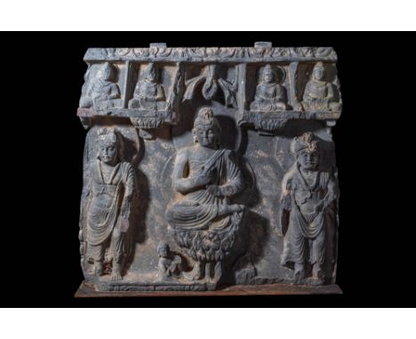 Ca. AD 2-3rd Century. A panel depicting the Preaching Buddha, atop a lotus pedestal supported by a lion throne. He is flanked