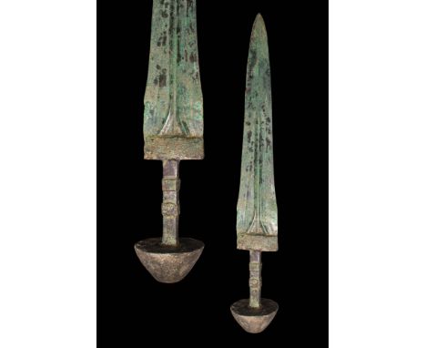 Ca. 1000 - 800 BC. A bronze sword with a broad blade with pronounced blood channels. The hilt terminates in a large conical-s