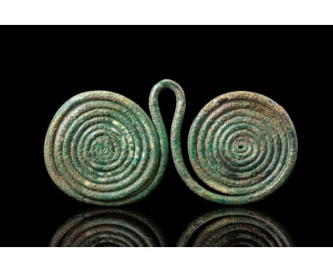 Ca. 1500 - 1200 BC.A pendant formed from a single rod of bronze wound into two symmetrical spirals, joined at the centre by a
