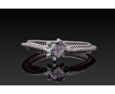 Ca. AD 900 - 1100. A silver bracelet composed of a plaited circular band with a central fastening element. The clasp is forme