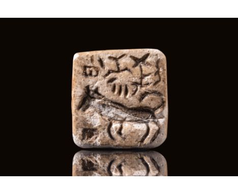 Ca. 2300 BC. A square plaque with a V-shaped suspension loop of one piece on the back. The design on the face shows a prancin