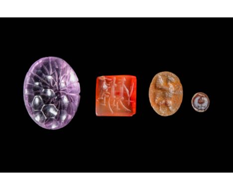 Ca. 500 BC - AD 600. A collection of four gems. On the far left, a pale purple amethyst carved into an oval with a radiating 