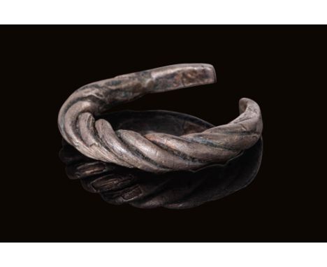 Ca. AD 900 - 1000. A silver ring formed from a single rod of thick wire twisted evenly into a tight spiral. The twisting crea