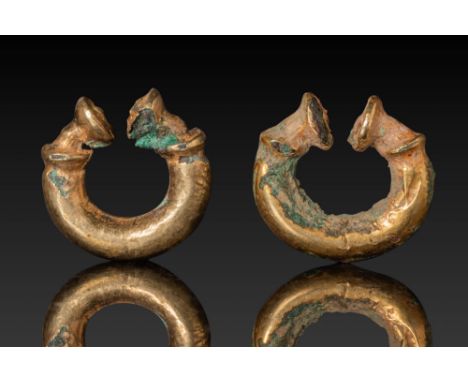 Ca. 100 BC. A matched pair of gold crescent-shaped hoop earrings. Each terminal ends in a flat disc-like expansion bordered b