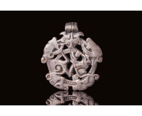 Ca. AD 800 - 1100. A silver pendant of circular form with an openwork design. The plaque is decorated with four projecting an