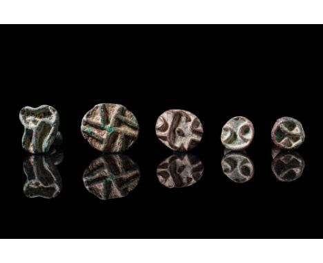 Ca. 2200 - 1500 BC. A collection of five bronze stamp seals. One is round with a compartmented face and tall stalk handle, an