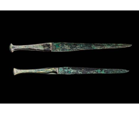 Ca. 1000 - 800 BC. A pair of bronze daggers, each with a narrow, tapering blade and a flanged hilt that expands slightly into