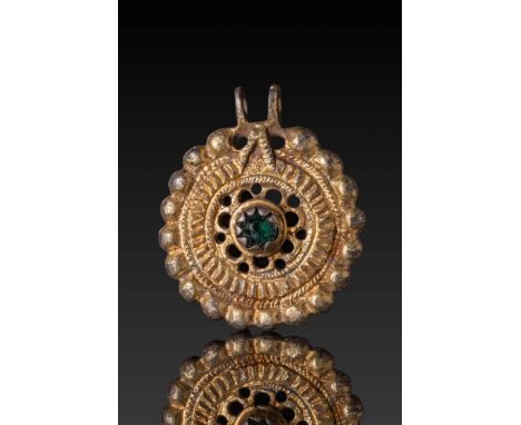 Ca. 1200 AD. A bronze-gilded pendant with a circular, beaded border enclosing a concentric arrangement of decorative bands. A