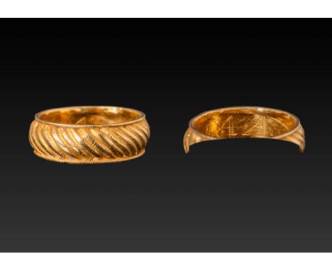 Ca. AD 1200 - 1600.A gold ring with a broad band encircled by a continuous pattern of raised diagonal ridges bordered by patt