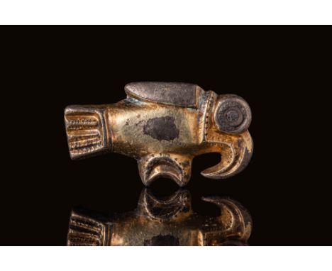 Ca. AD 500 - 700. A gilt-bronze brooch in the form of a bird with a broad tail and sharply curved beak. The eye is rendered a