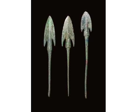 Ca. 1000 - 800 BC. A collection of three bronze arrowheads, each with a broad triangular blade and deep side notches forming 