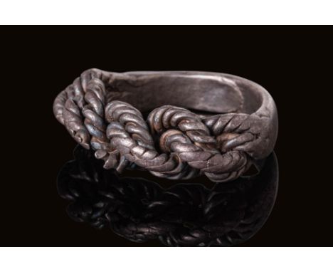 Ca. AD 900 - 1000. A silver ring composed of three tightly braided ropes joined at the back by a solid, flat band. Each stran