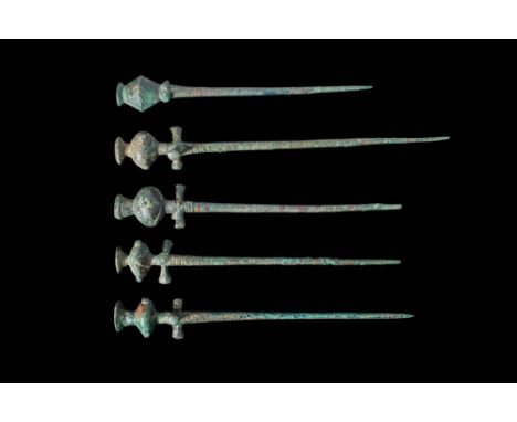 Ca. 1000 - 800 BC. A collection of five bronze pins with cast, solid shafts tapering to sharp points. Each is topped with a p