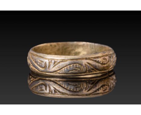 Ca. AD 1400 - 1600. A silver-gilt ring with a flat band, incised with a continuous scrolling vegetal motif. The design is bor