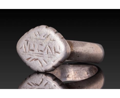Ca. AD 800 - 1100. A silver ring with a flat, scalloped bezel engraved with a pseudo-Kufic inscription. The engraved lines ar