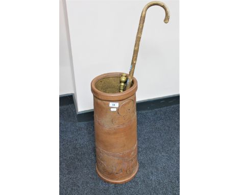 An earthenware stick pot containing a Victorian fire poker and a walking stick with various badges