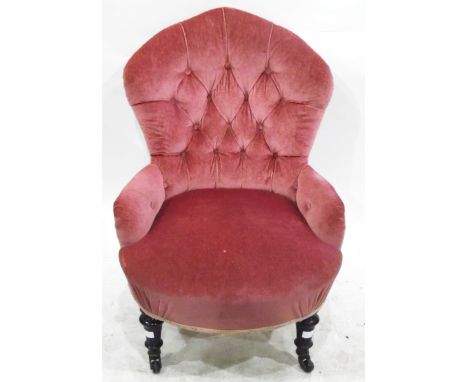 Victorian low nursing chair, the pink upholstery with button back and short ebonised supports 