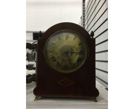 Early 20th century inlaid and stained wood bucket-style mantel clock having broken arch top with four pineapple finials, engr