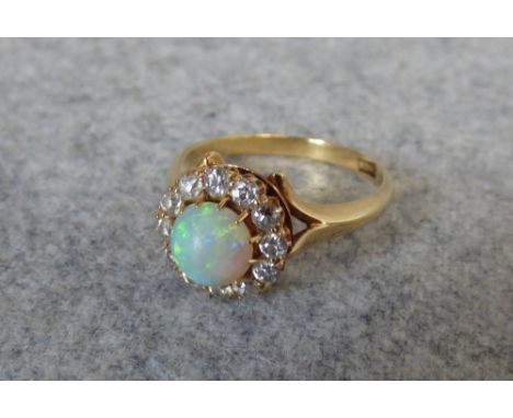 Opal and diamond cluster ring, circa 1910, the round cabochon enclosed by twelve small old cuts totalling approx. 0.6 carats,