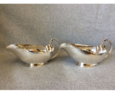 A large pair of Danish design Arts & Crafts oval silver sauce boats with cast leaf & bead capped scroll handles, bears maker'