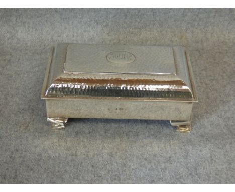 Silver trinket box by 'A & J Zimmerman', Birmingham 1907, hammered hinged cover, monogrammed cartouche on four supports, 11.5