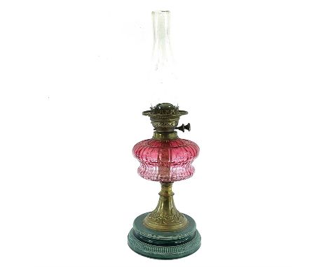 A Victorian oil lamp, with a cranberry glass reservoir on a brass and ceramic base, height 36cm.No condition issues.