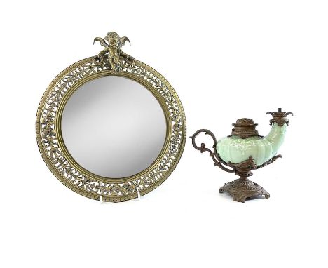 A late 19th century Continental oval pierced brass mirror, surmounted by a winged cherub, together with a celadon glazed tabl