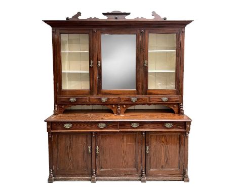 A late Victorian pitch pine kitchen dresser, the upper part with a mirroed and two glazed doors above four spice drawers, the